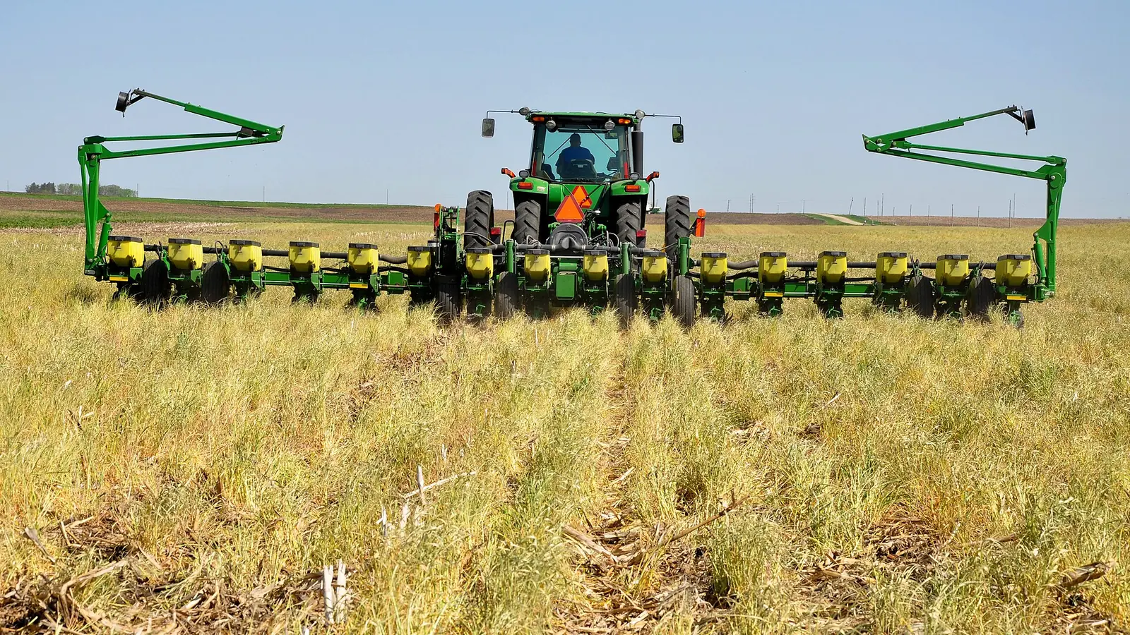 A tractor pulling a wide no-till planter across an Iowa field