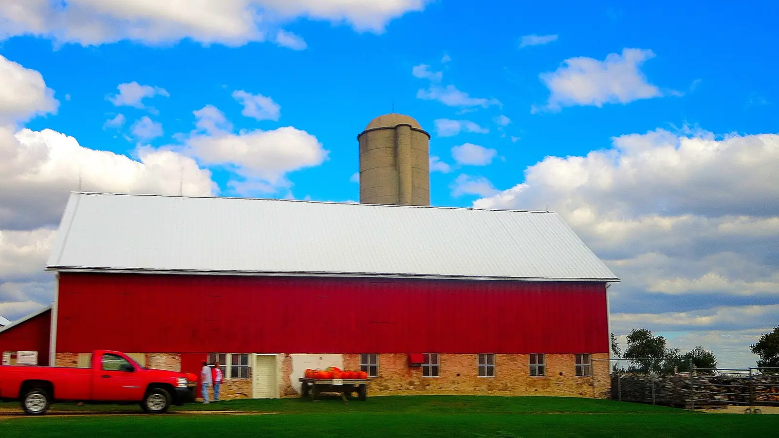 A bright red barn with a silo under a blue sky in Wisconsin